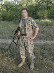 Photographie d'un braconnier en tenue camouflée et avec son arme.