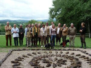Photographie d'un groupe de chasseurs devant une mise en scène d'un massacre d'animaux.