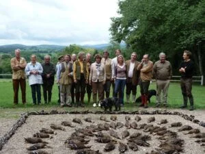 Photographie d'un groupe de chasseurs devant une mise en scène d'un massacre d'animaux.